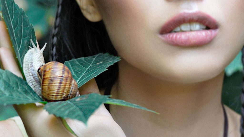 Woman with smooth skin holding a snail